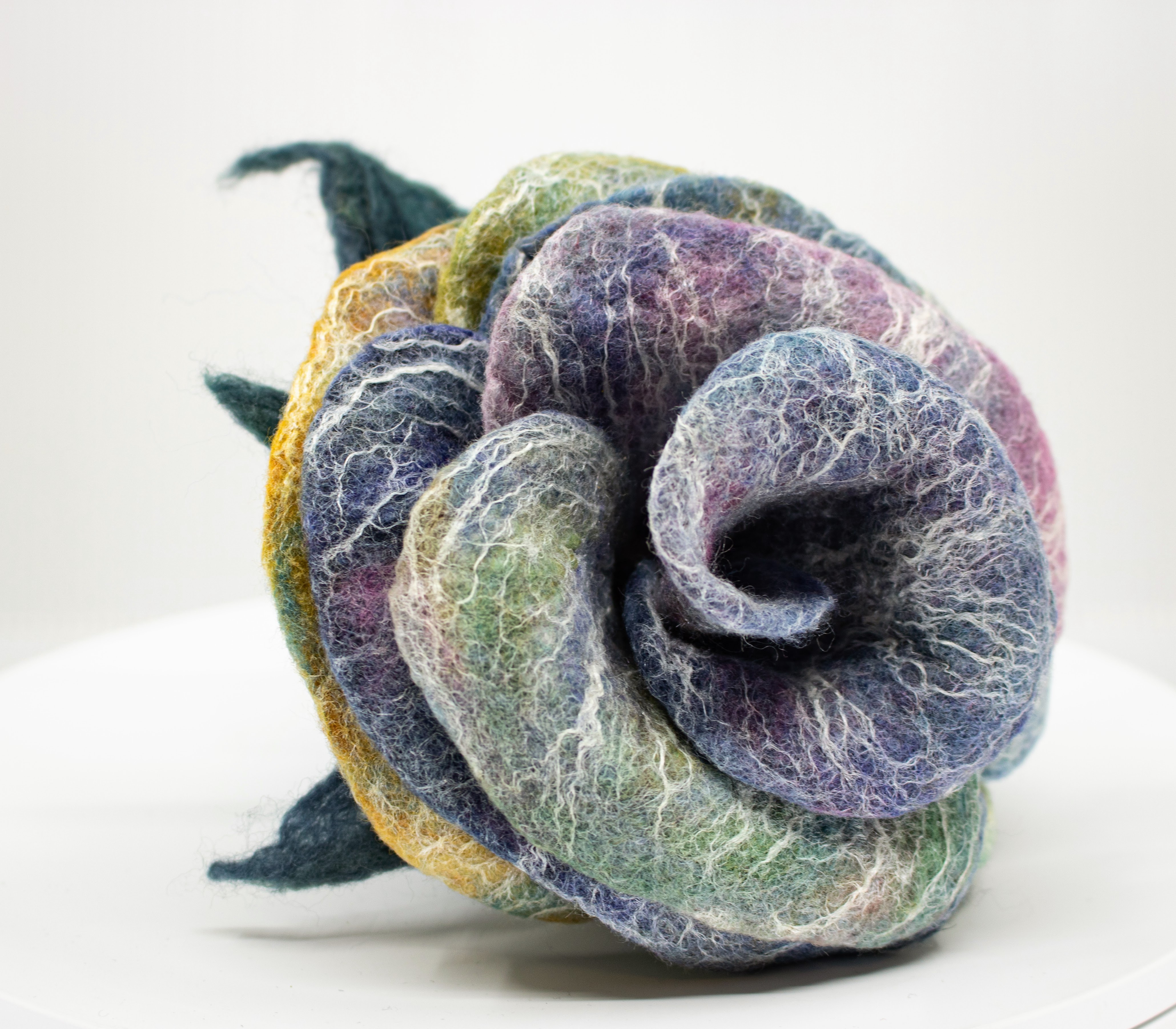 Close-up of a handmade felted wool rose sculpture with soft blended layers of periwinkle, olive, and lavender