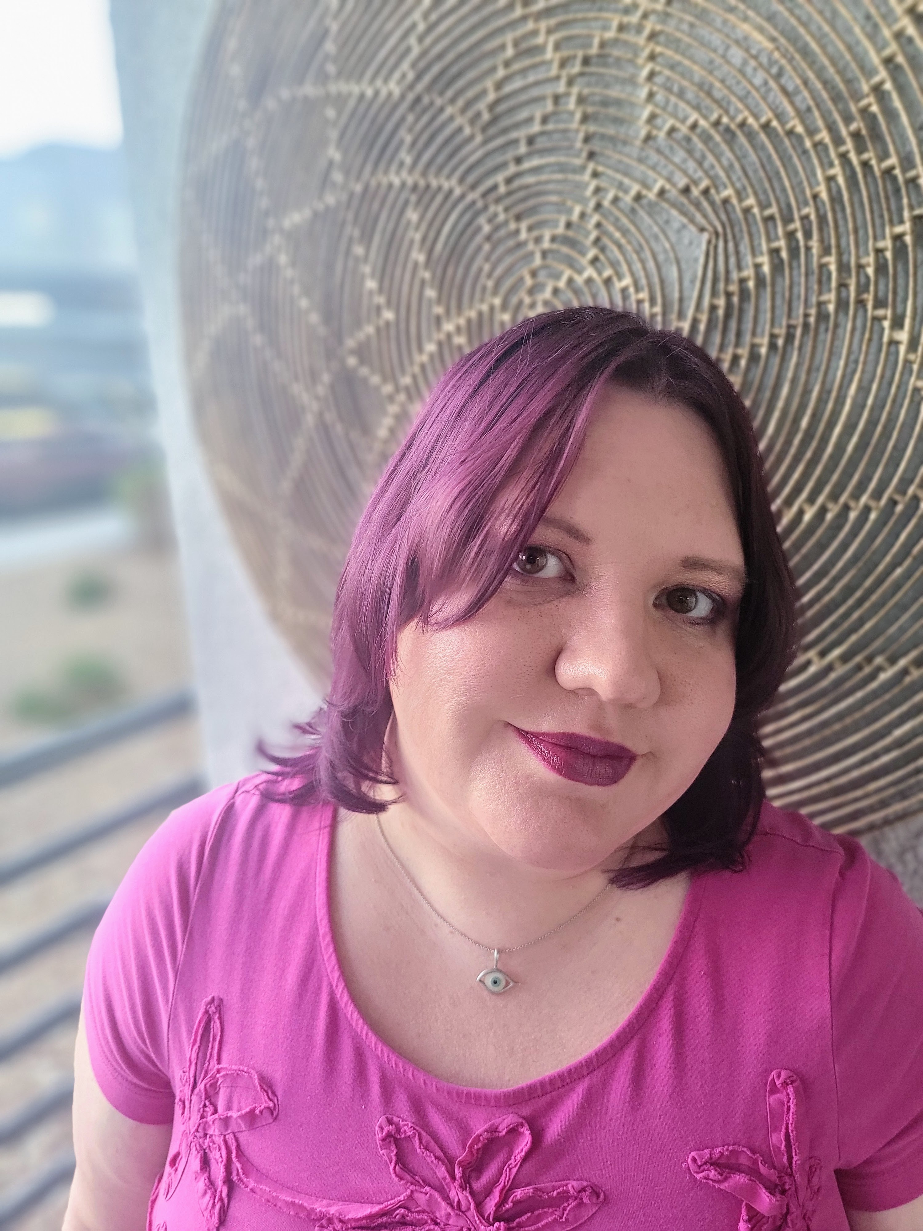 Portrait of Las Vegas artist Lindsey McConnell with violet hair wearing an evil eye necklace